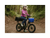 A woman on a trail in a forest sitting on a green cargo ebike with a small front basket and large rear basket wearing a pink jacket and white helmet.